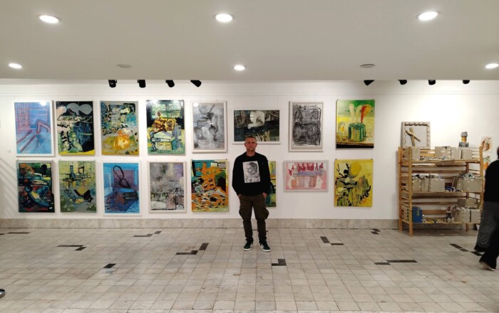 Aleksandar in front of his paintings